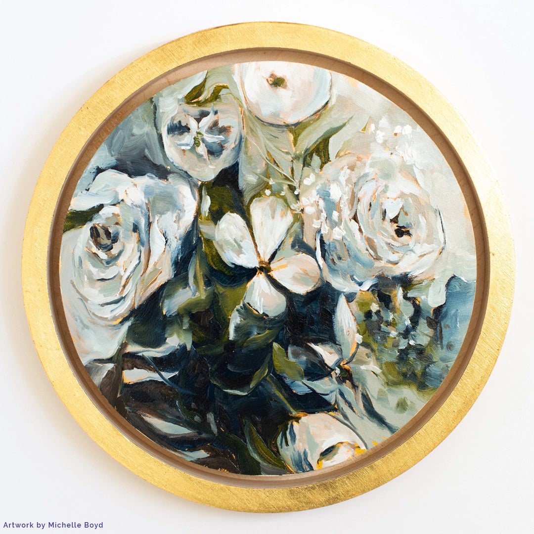 White flowers with dark green foliage painted inside a gold circular frame.