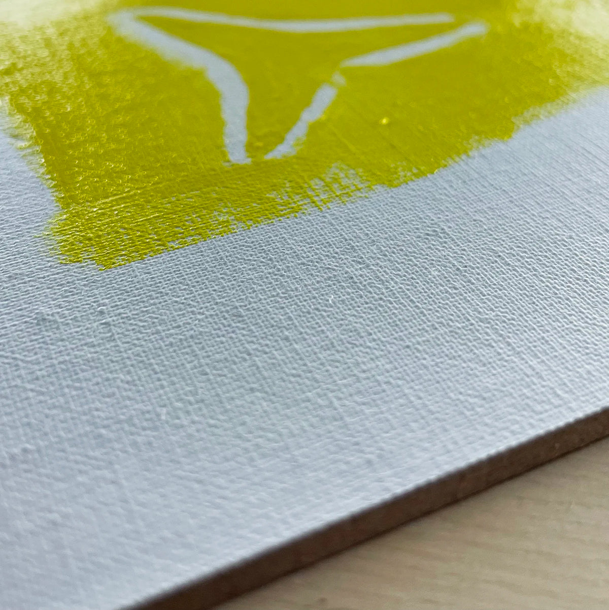 Close-up of a yellow painted swatch on white woven linen.