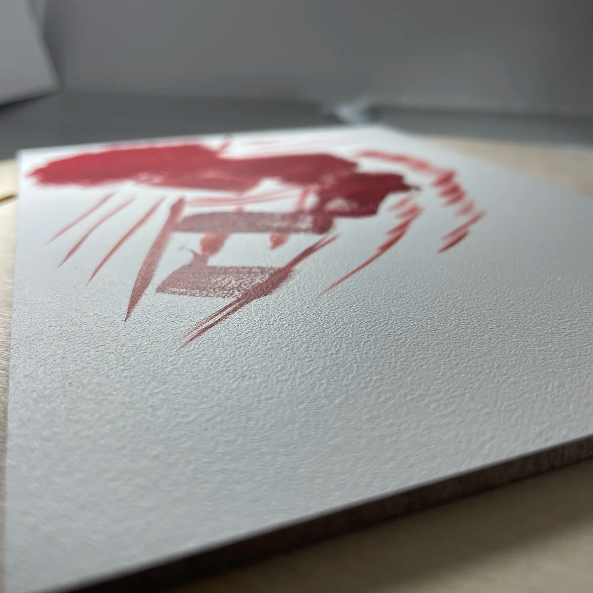 Close-up of red brushstrokes on a white oil-ground panel.