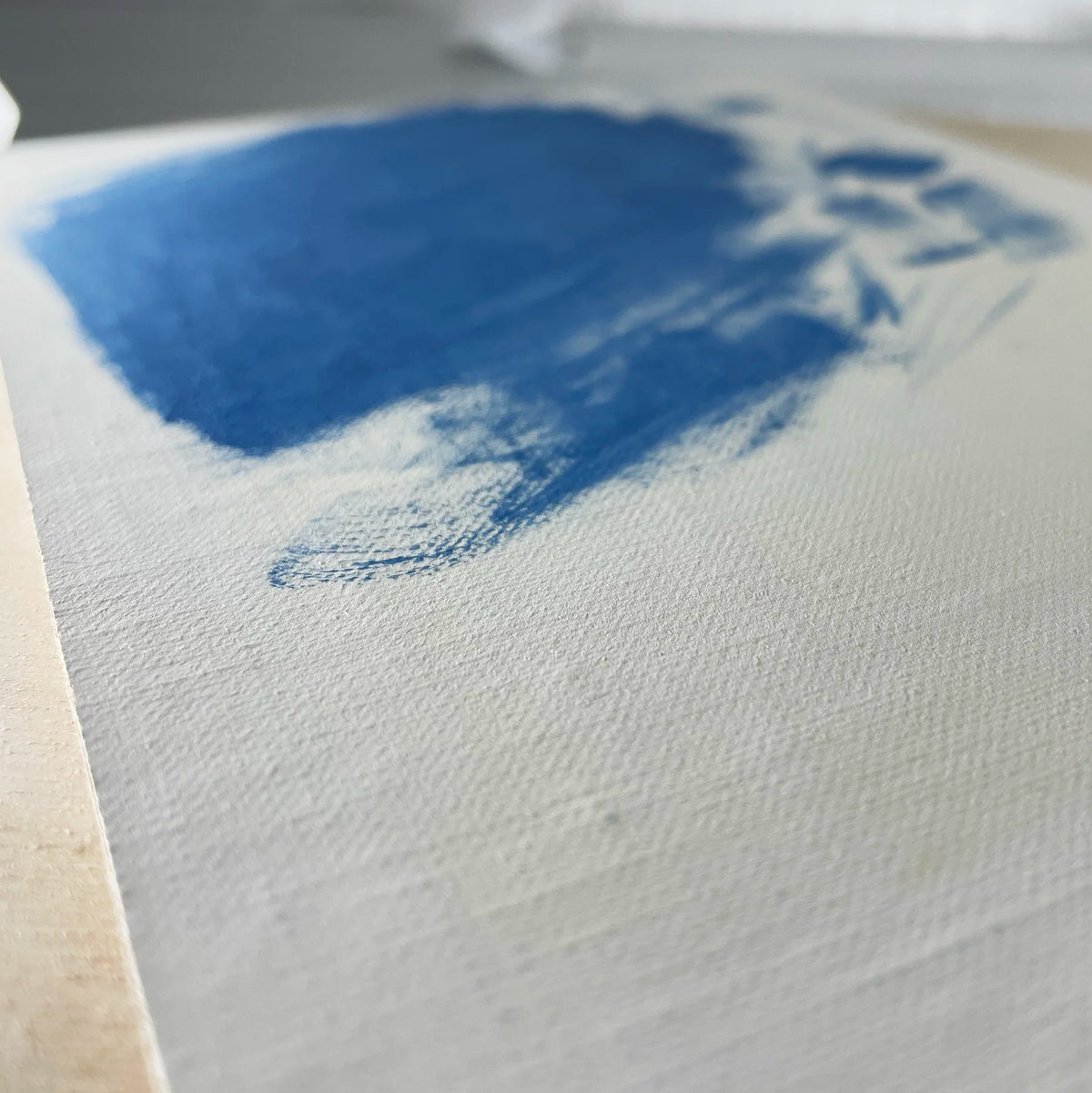 Close-up of a blue painted swatch on pale textured linen.