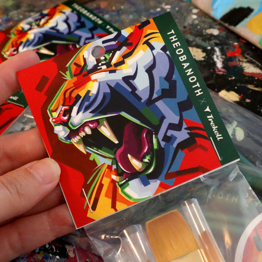Hand holds illustrated brush-set packaging with a faceted rainbow creature.