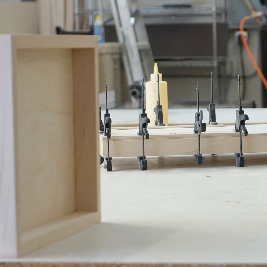 Panel-making equipment and clamps beside a pale wooden support frame.