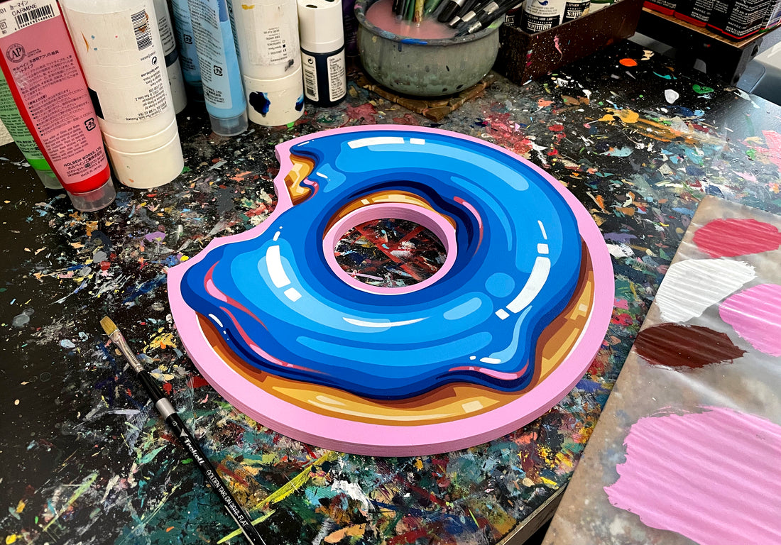 Blue-frosted doughnut-shaped panel on a paint-covered studio table.