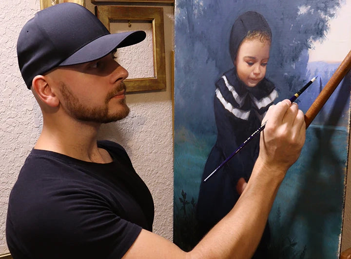 Artist in a cap paints a child's portrait at an easel.