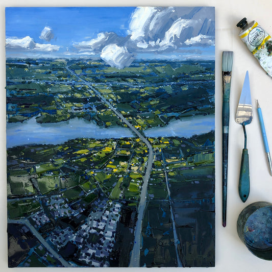 Painted landscape panel beside brushes and paint tubes.