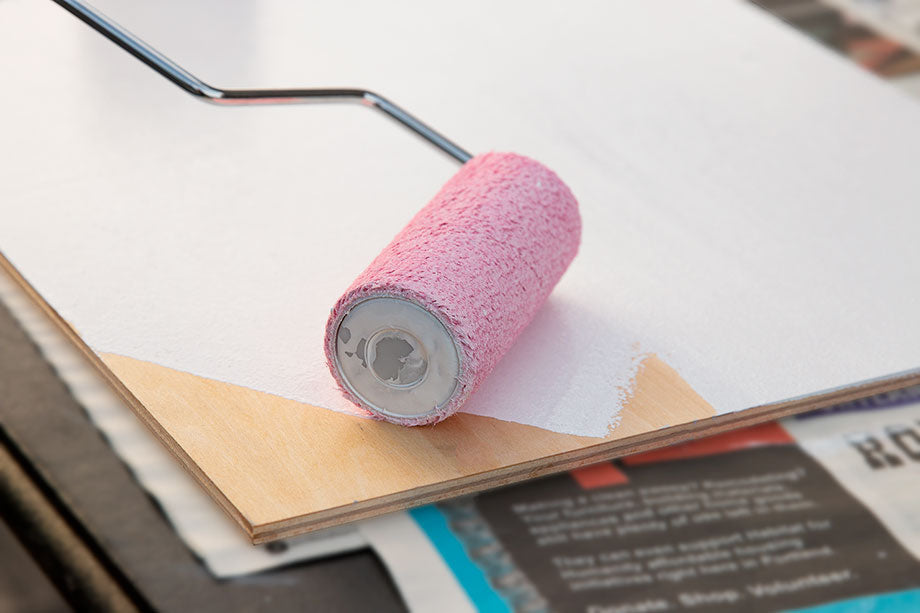 Pink foam roller rests on a white rectangular panel.