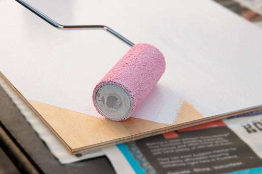 Pink foam roller rests on a white rectangular panel.