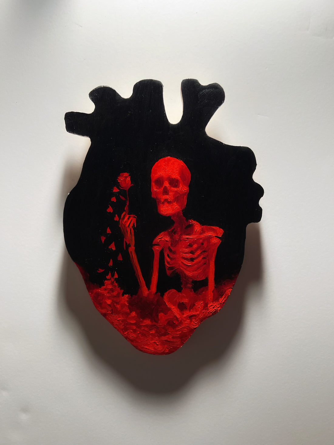 Red skeleton painted on a black anatomical-heart panel.
