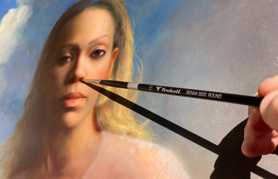 Two brushes held in front of a woman's portrait.