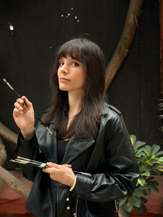 Dark-haired woman holds a glass and gestures in a dim studio.