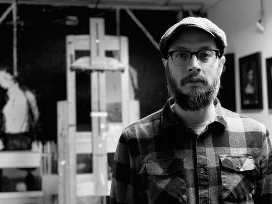 Black-and-white portrait of a bearded man in glasses and a cap.