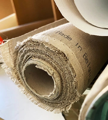 Close-up of coarse beige linen rolled around a cardboard tube.