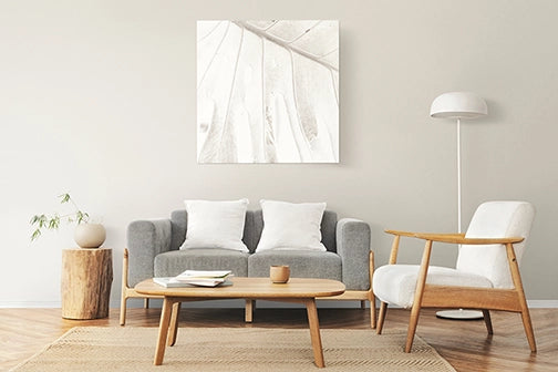 Bright living room with a gray sofa, pale chairs and a white wall lamp.