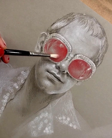 Brush adds red paint to round goggles on a grayscale woman's portrait.