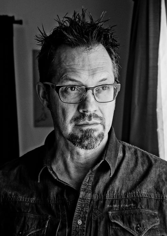 Black-and-white portrait of a man with glasses and tousled hair.