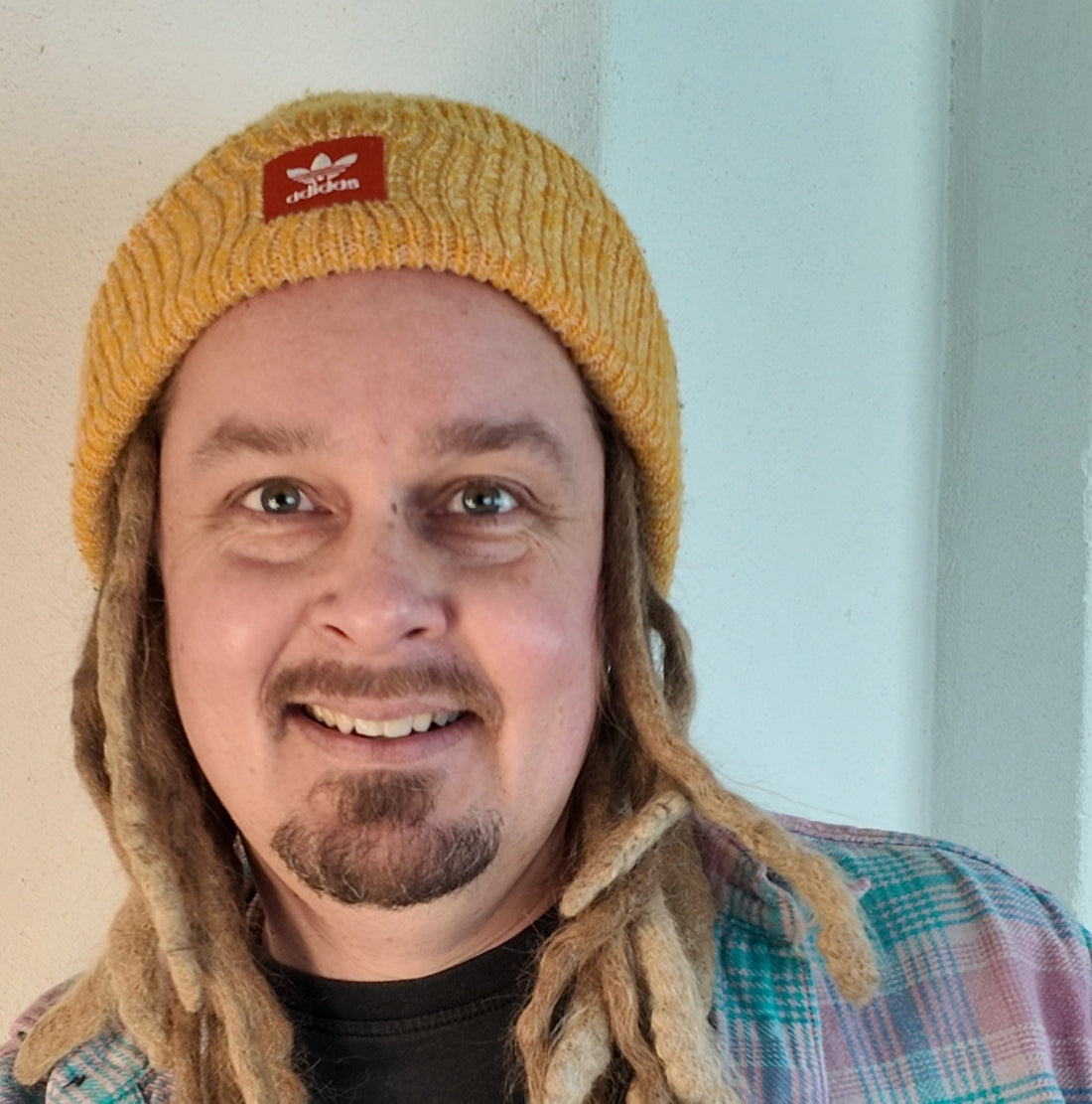 Smiling man in a yellow knit cap and plaid shirt.