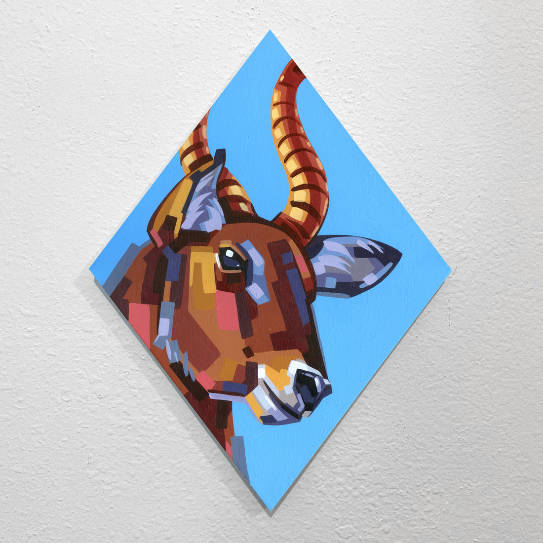 Faceted orange-and-brown antelope head on a blue diamond-oriented panel.
