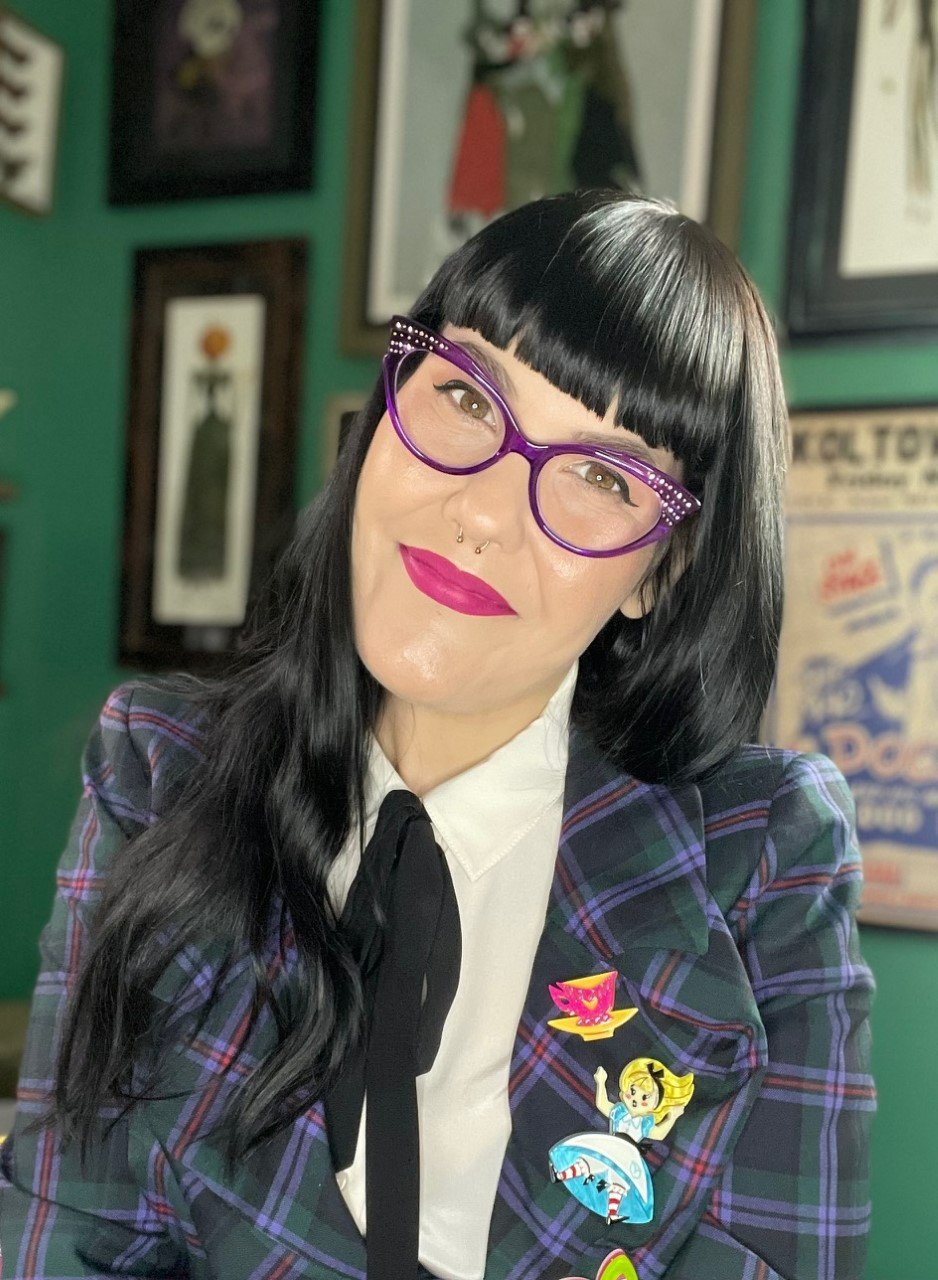 Woman with dark hair and purple glasses in a studio.
