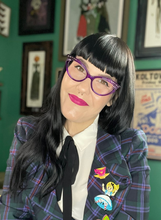 Woman with dark hair and purple glasses in a studio.