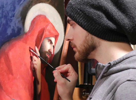 Artist in a gray beanie paints a red-robed figure.