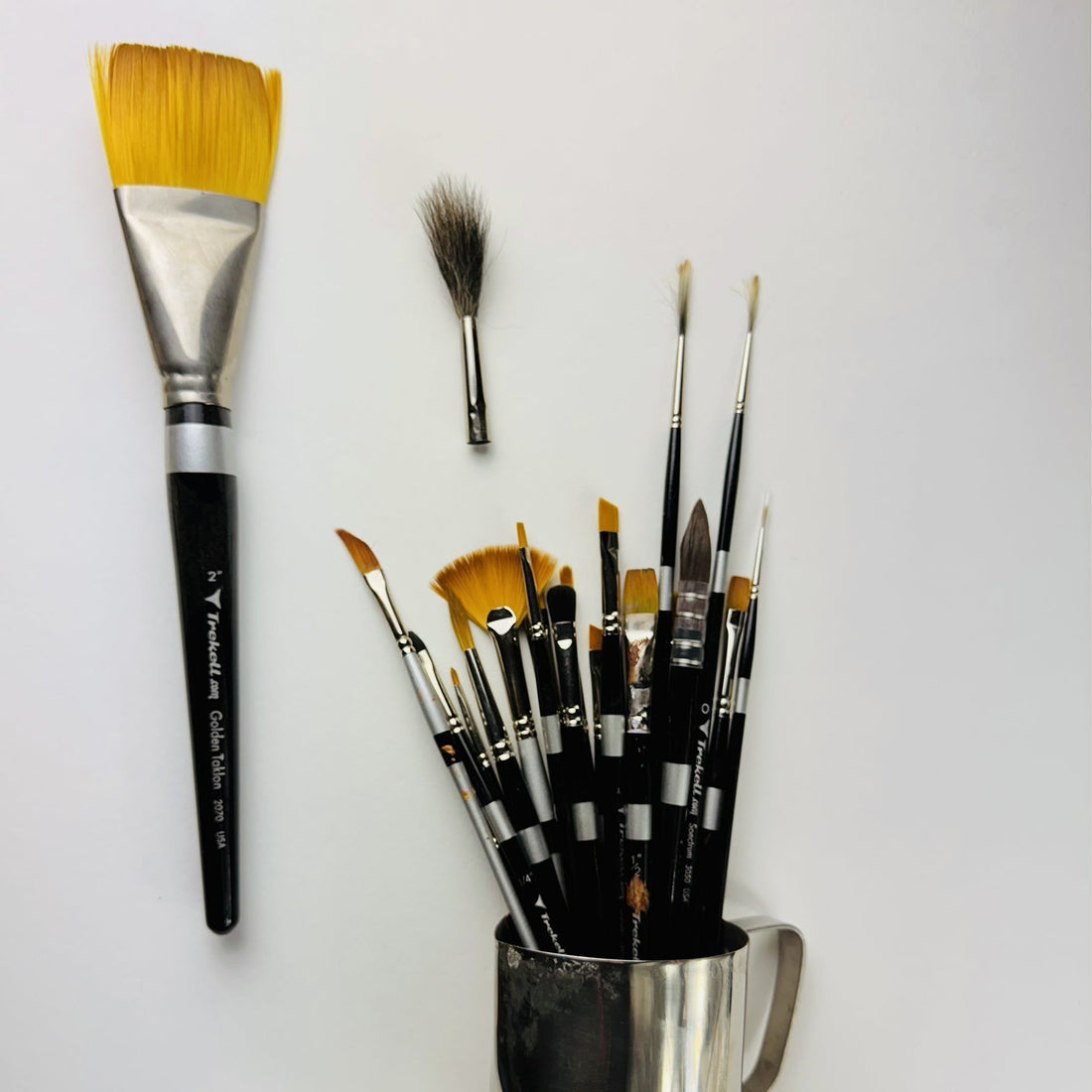 Large golden wash brush, dark mop brush and a jar of assorted brushes.