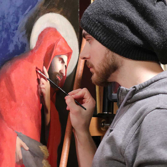 Artist in a gray beanie paints a red-robed figure.