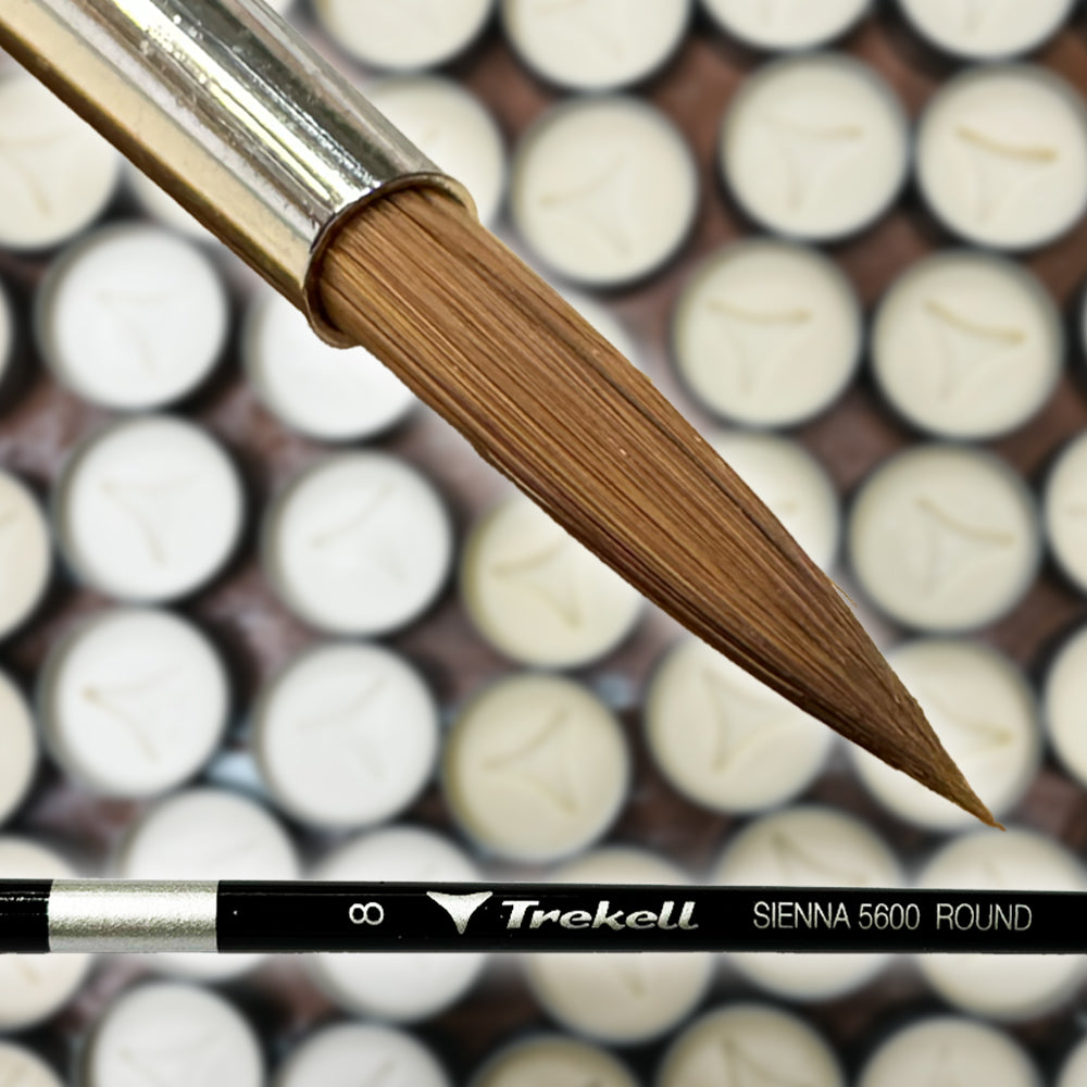 Close-up of a large brown brush tip above small paint pots and a black brush handle.