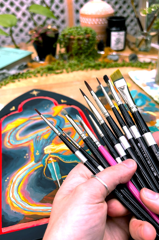 Brush Restorer jar above a hand holding brushes over a snake painting.