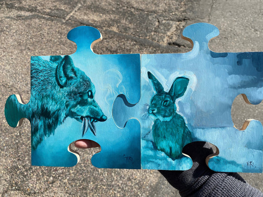 Two joined puzzle-piece panels painted in blue tones: a snarling wolf on the left faces a rabbit on the right.