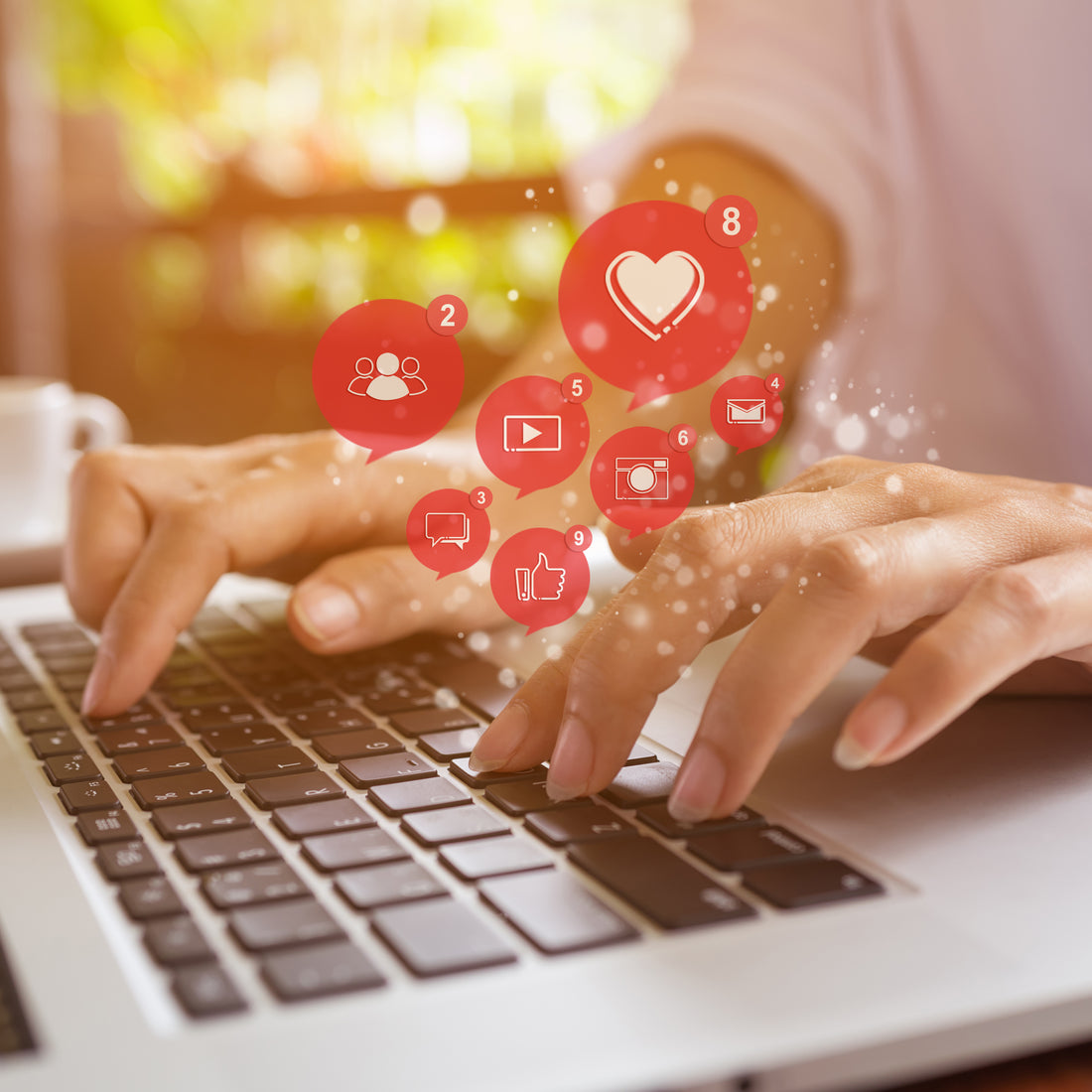 Hands type on a laptop beneath floating red heart icons.