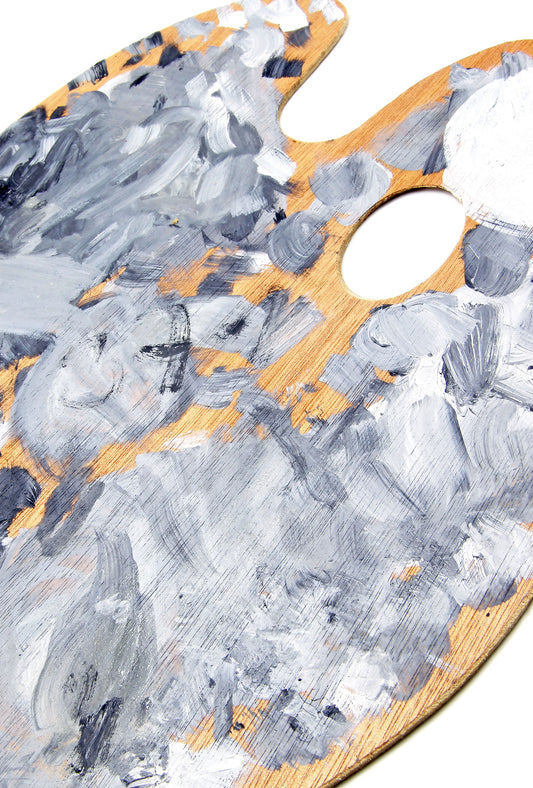 Hand squeezes orange paint onto a gray-and-orange paint-covered palette.