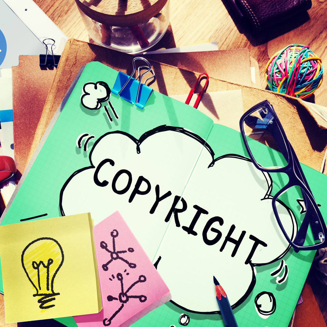Copyright lettering in a cloud shape over a collage of papers and art supplies.