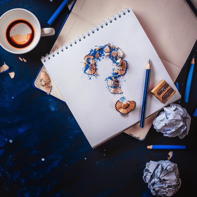 Small colorful artwork and art tools arranged on a spiral-bound sketchbook.