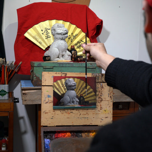 Artist reaches toward a red-and-gold shrine-like painting.