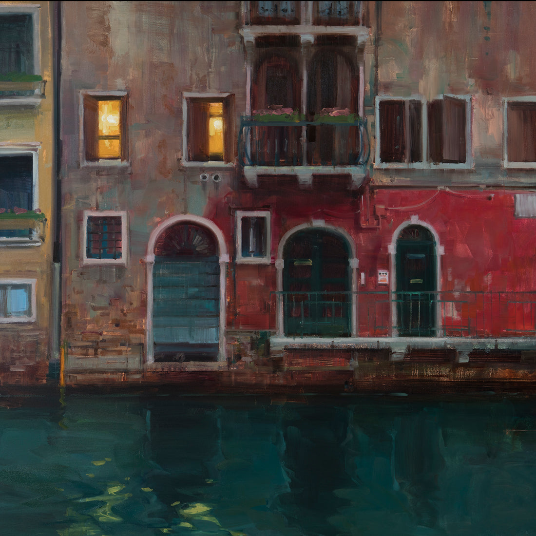 Red-brick buildings with illuminated windows reflected in dark green water.