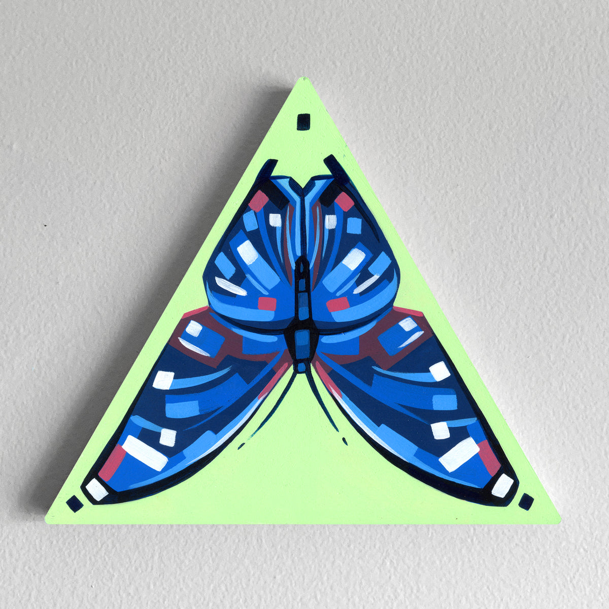 Blue butterfly painted on a lime-green triangular panel with a hanging hole.