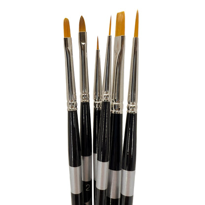 Six black-handled brushes fanned upright with long golden pointed and flat tips.