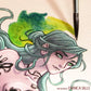 Close-up of a green-haired illustrated woman beside a pointed brush and green watercolor wash.
