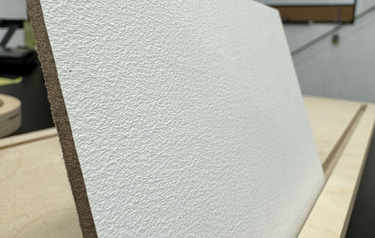 Close-up of a white primed panel showing its textured surface and straight edge.