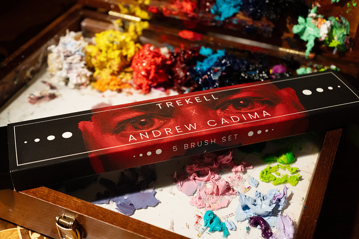 Andrew Cadima brush set box on a wooden palette covered with colorful paint.