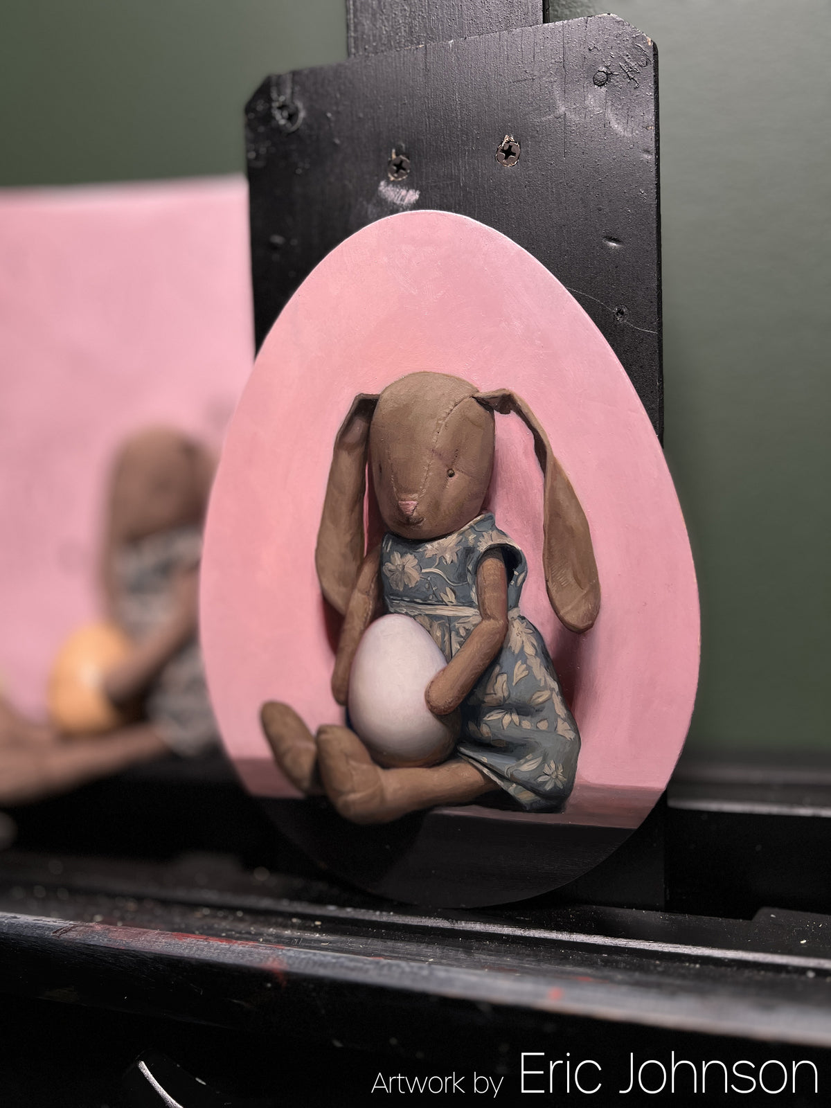 Pink egg-shaped panel painted with a seated elephant-headed figure, credited to Eric Johnson.