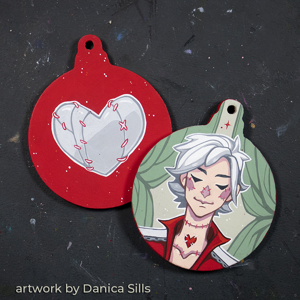 Two round ornaments painted with a heart and a white-haired character, credited to Danica Sills.