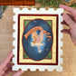 Hands hold a postage-stamp panel painted with a winged envelope on a dark blue oval.
