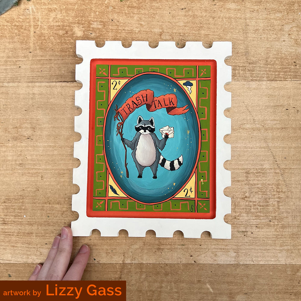 Postage-stamp panel painted with a black-and-white animal on a blue oval, credited to Lizzy Gass.