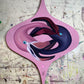 Purple-and-pink stylized bird painted on a pink retro ornament panel.