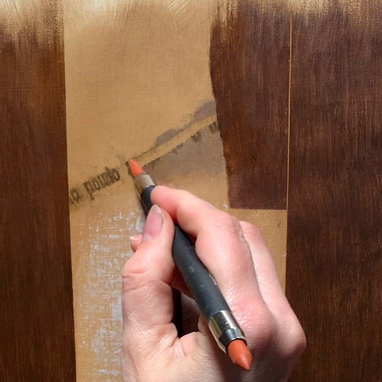 Hand uses a broad brush to apply a light brown coating to a wooden surface.