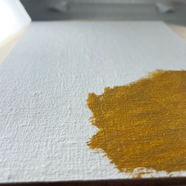 Close-up of textured white linen with an ochre painted swatch.