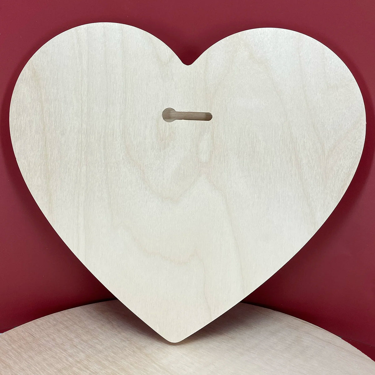 Symbolic heart panel back, bare wood with a horizontal keyhole slot against red.